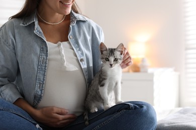 Pregnant woman with cute cat at home, closeup