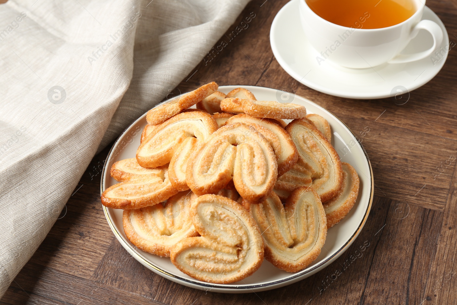 Photo of Tasty french palmier cookies and tea on wooden table, closeup