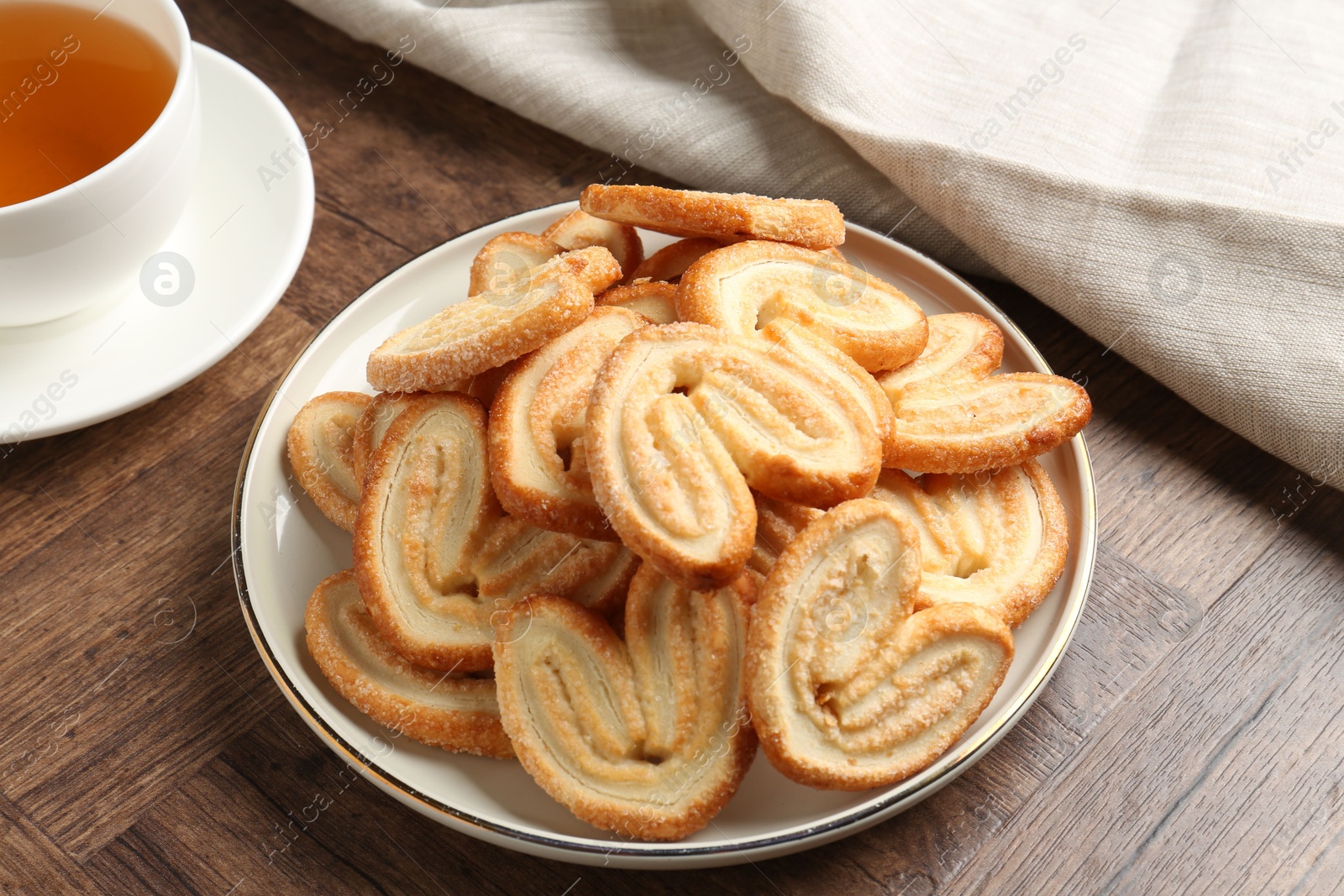 Photo of Tasty french palmier cookies and tea on wooden table, closeup