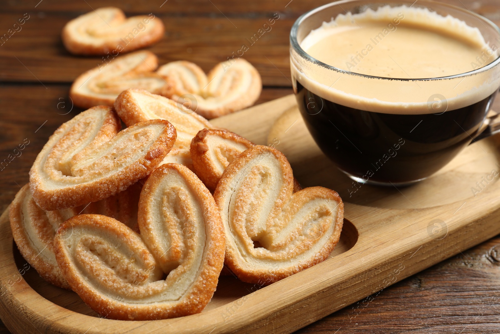 Photo of Tasty french palmier cookies and coffee on wooden table, closeup