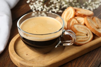 Photo of Tasty french palmier cookies and coffee on wooden table, closeup