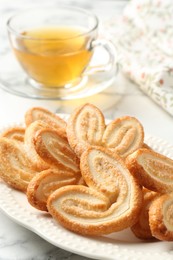 Photo of Delicious palmier cookies with tea on white table, closeup