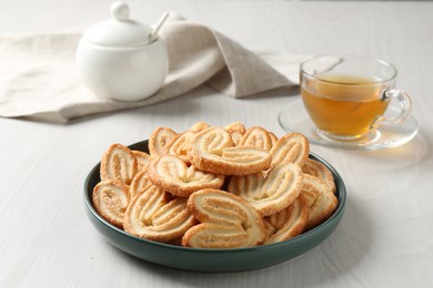 Photo of Delicious palmier cookies with tea on white wooden table