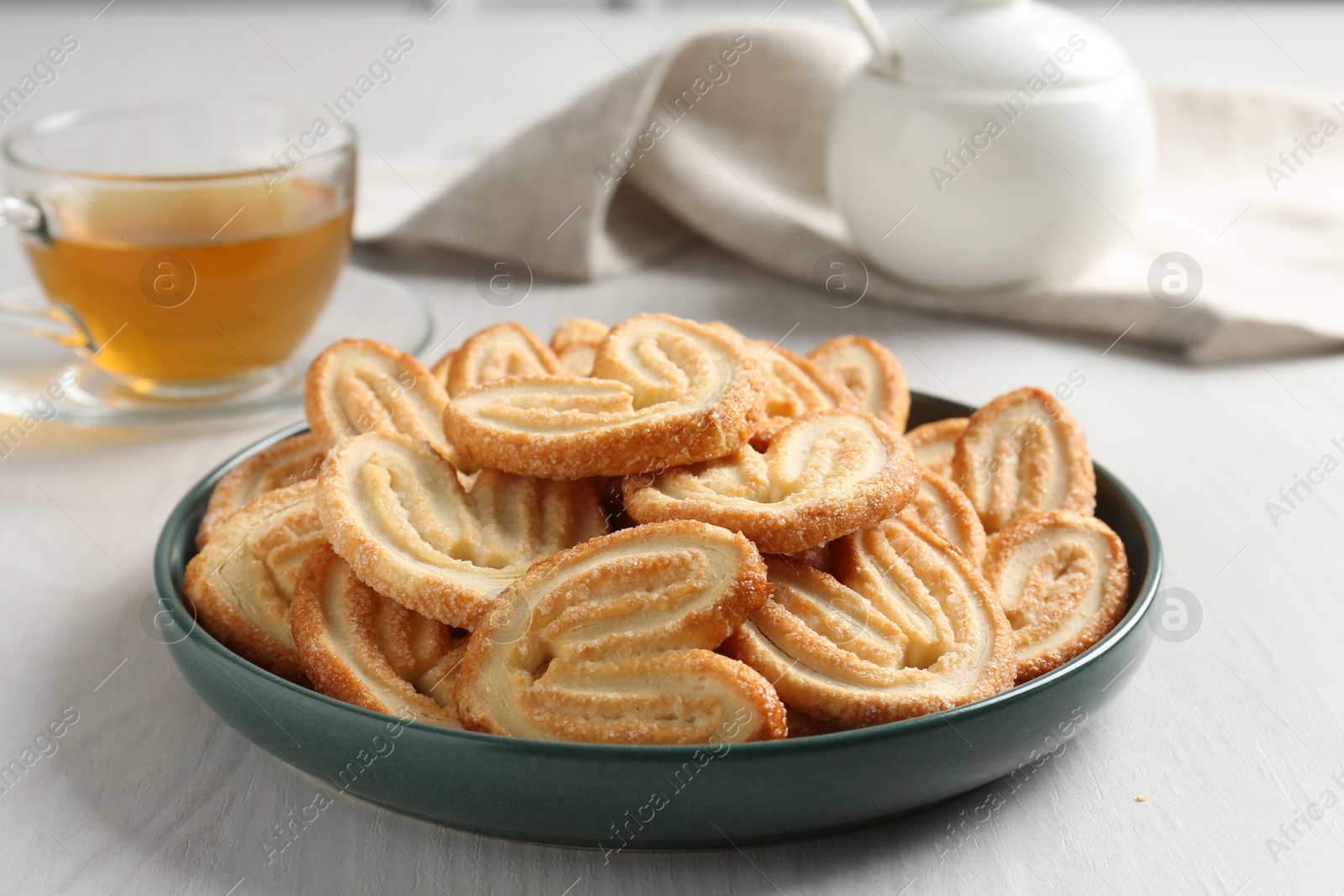 Photo of Delicious palmier cookies with tea on white wooden table, closeup