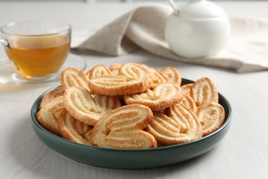 Delicious palmier cookies with tea on white wooden table, closeup