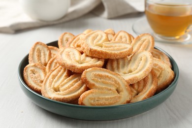 Photo of Delicious palmier cookies with tea on white wooden table, closeup