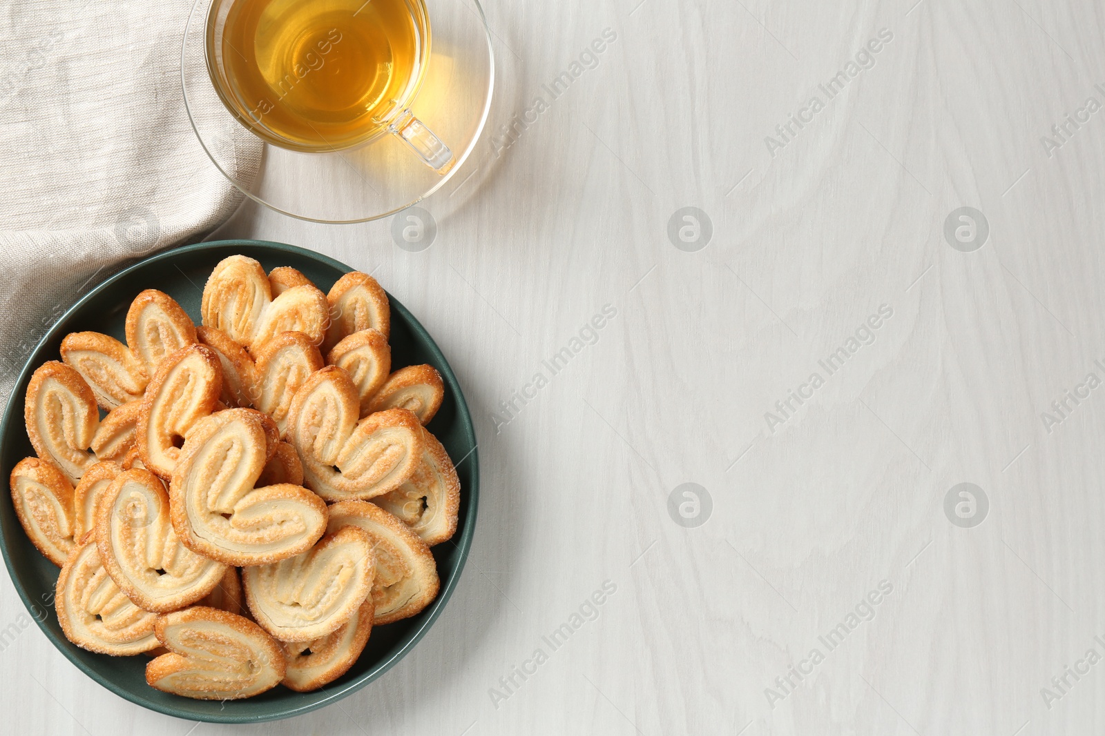 Photo of Delicious palmier cookies with tea on white wooden table, top view