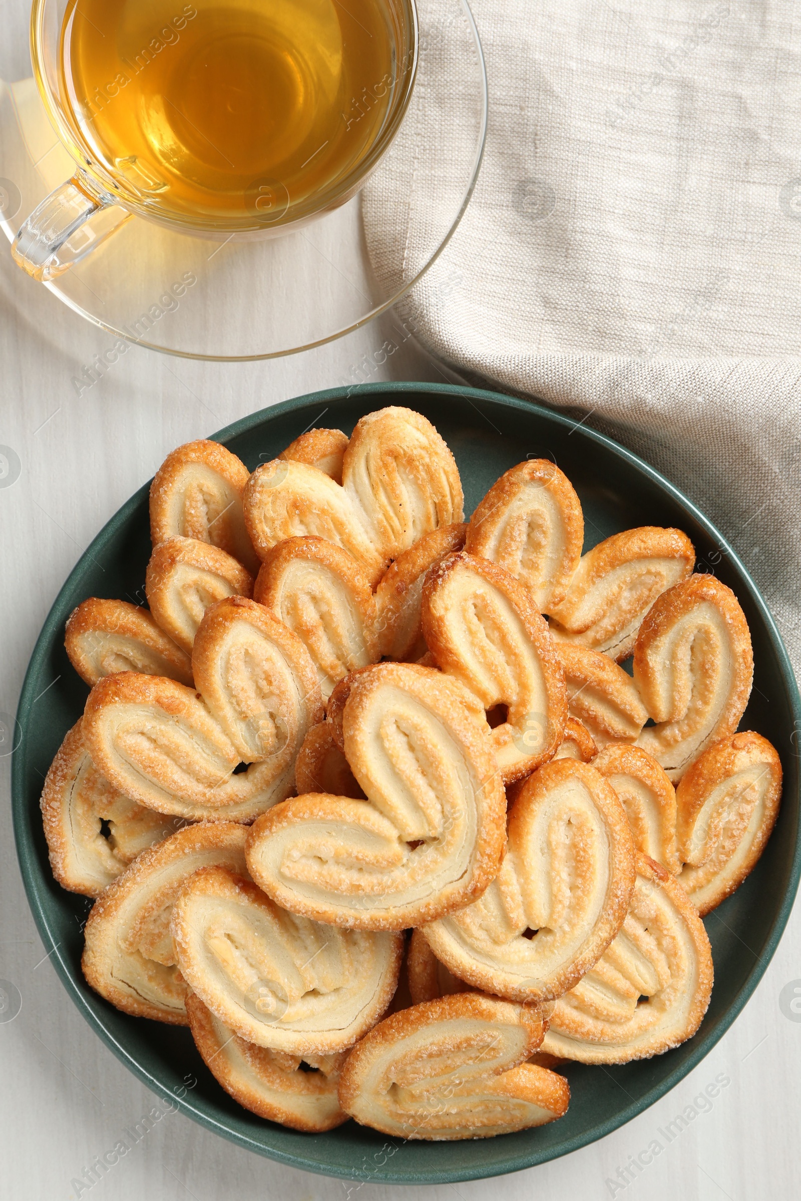 Photo of Delicious palmier cookies with tea on white wooden table, top view