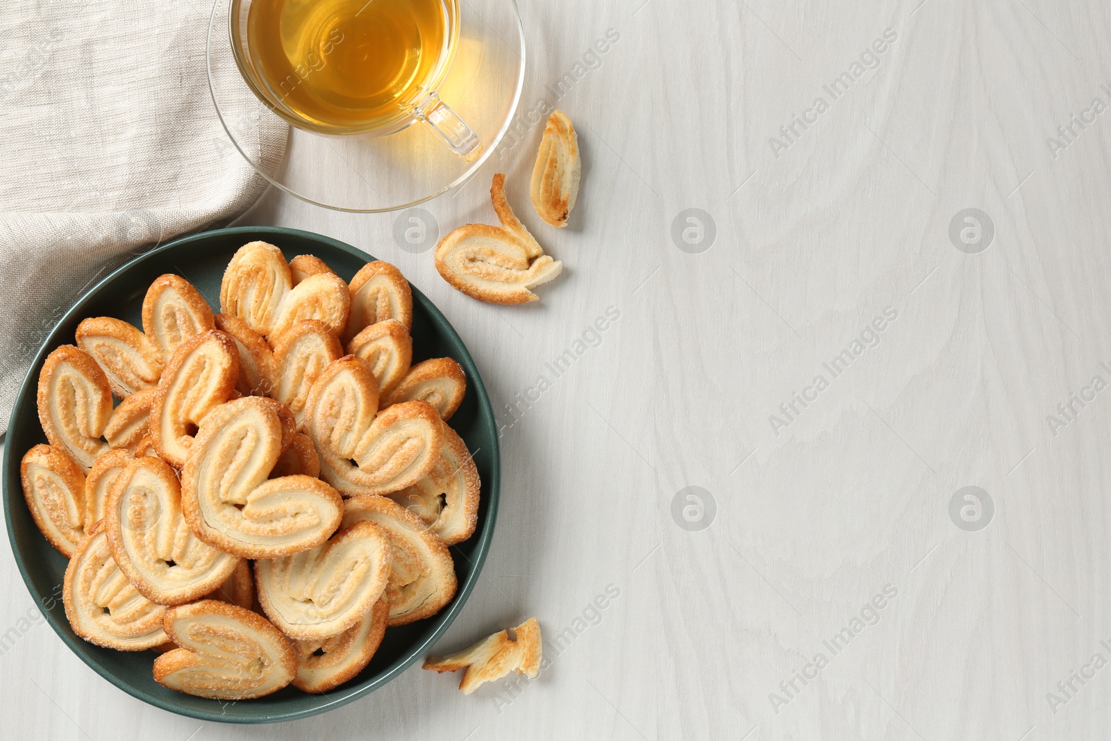 Photo of Delicious palmier cookies with tea on white wooden table, top view