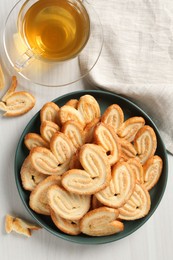 Photo of Delicious palmier cookies with tea on white wooden table, top view