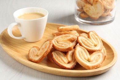 Photo of Delicious palmier cookies with coffee on white wooden table, closeup