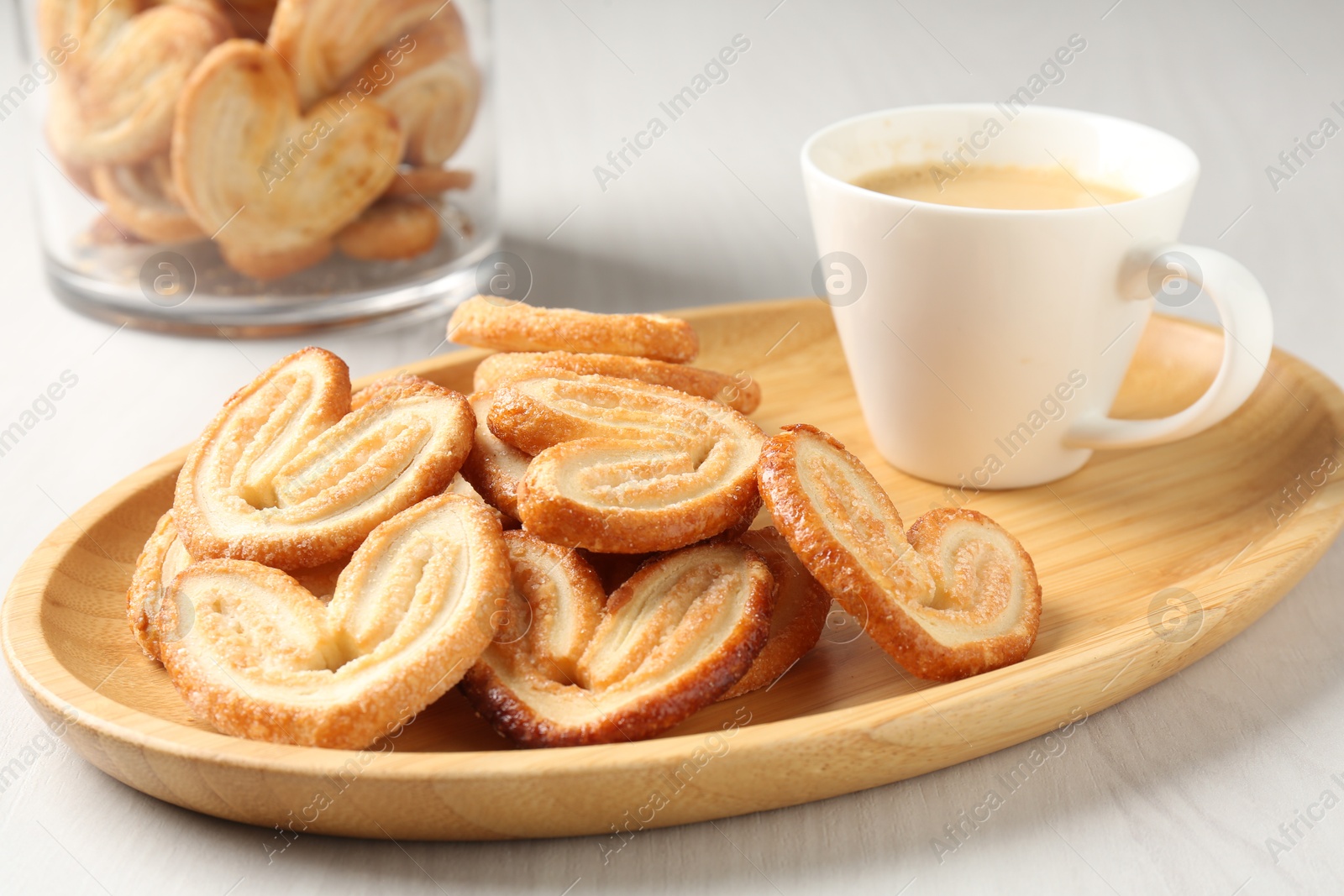 Photo of Delicious palmier cookies with coffee on white wooden table, closeup