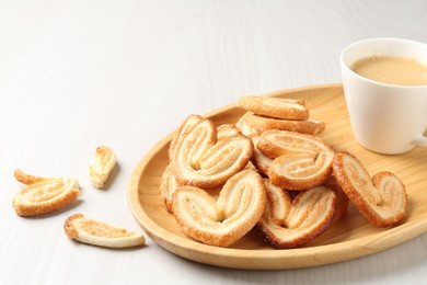 Photo of Delicious palmier cookies with coffee on white wooden table