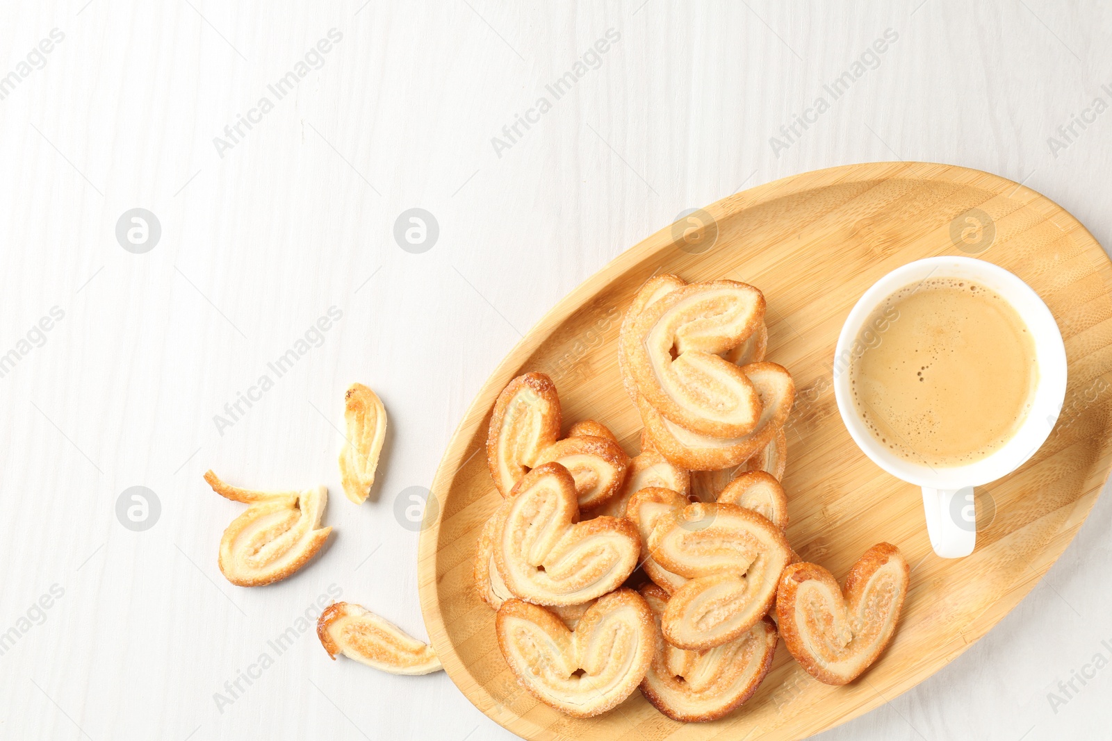 Photo of Delicious palmier cookies with coffee on white wooden table, top view