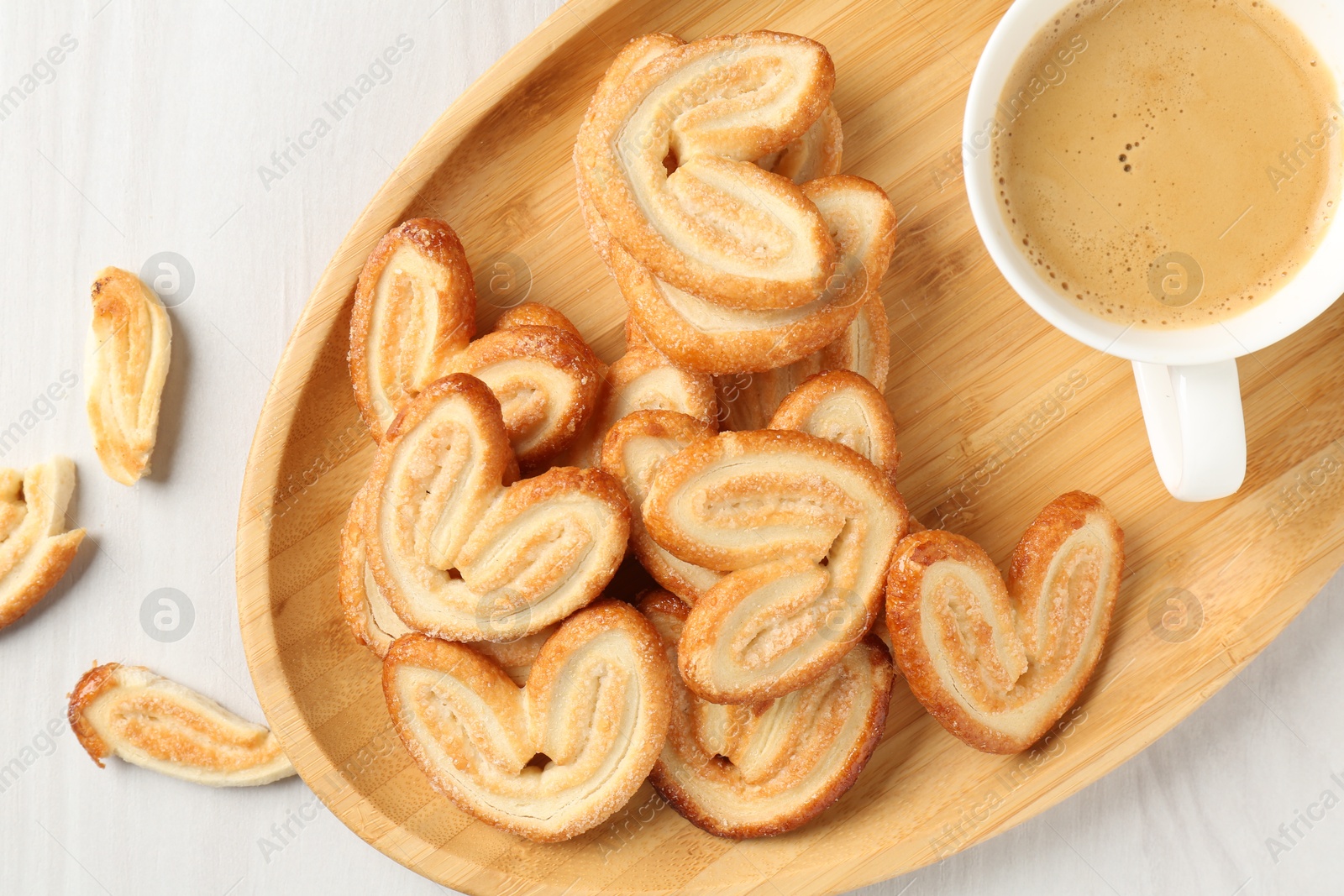 Photo of Delicious palmier cookies with coffee on white wooden table, top view