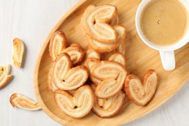 Photo of Delicious palmier cookies with coffee on white wooden table, top view