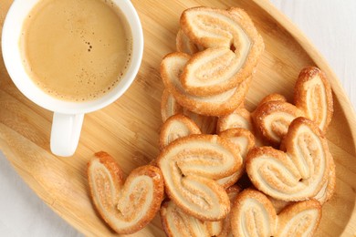 Photo of Delicious palmier cookies with coffee on white wooden table, top view