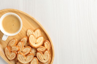 Photo of Delicious palmier cookies with coffee on white wooden table, top view