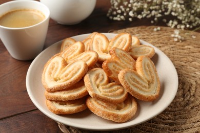 Photo of Delicious palmier cookies with coffee on wooden table