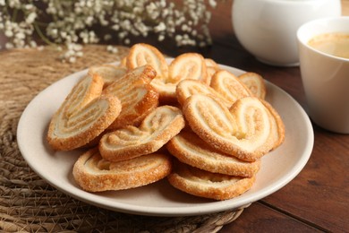 Photo of Delicious palmier cookies with coffee on wooden table