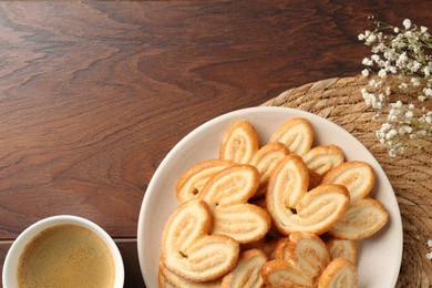 Photo of Delicious palmier cookies with coffee on wooden table, flat lay