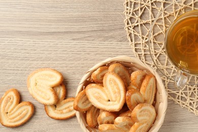 Photo of Delicious palmier cookies with tea on wooden table, flat lay