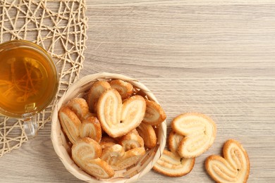 Photo of Delicious palmier cookies with tea on wooden table, flat lay