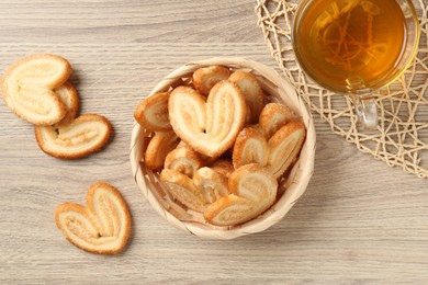 Photo of Delicious palmier cookies with tea on wooden table, flat lay