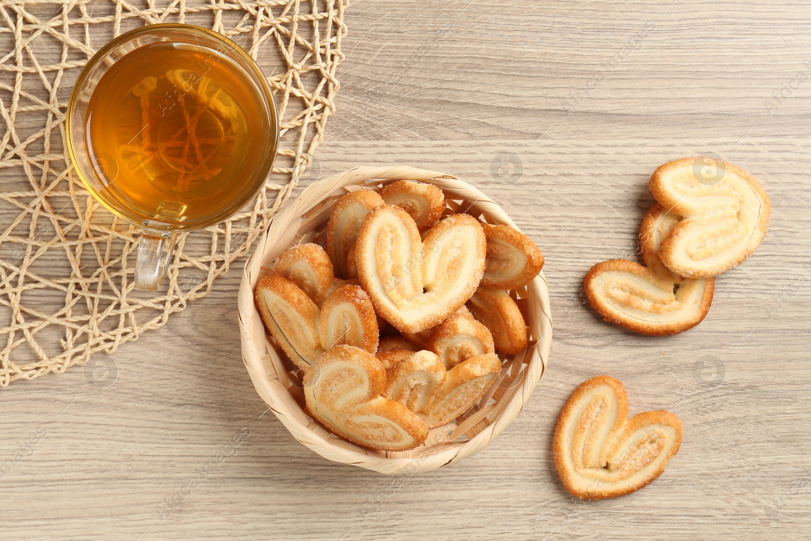 Photo of Delicious palmier cookies with tea on wooden table, flat lay