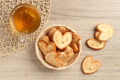 Photo of Delicious palmier cookies with tea on wooden table, flat lay