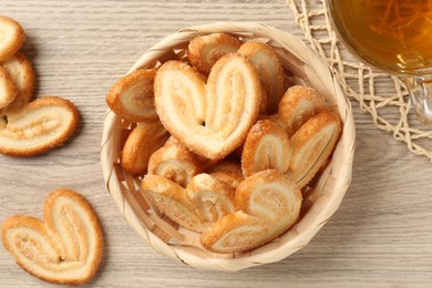 Photo of Delicious palmier cookies with tea on wooden table, flat lay