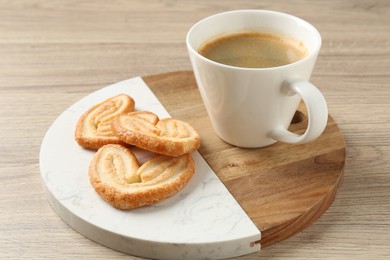 Photo of Delicious palmier cookies with coffee on wooden table