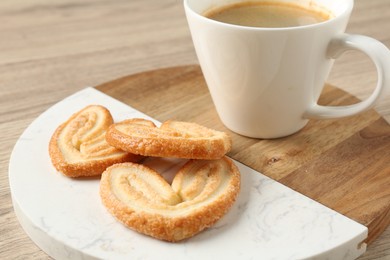 Photo of Delicious palmier cookies with coffee on wooden table