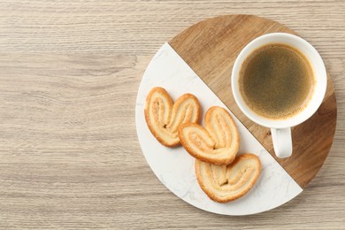 Photo of Delicious palmier cookies with coffee on wooden table, top view