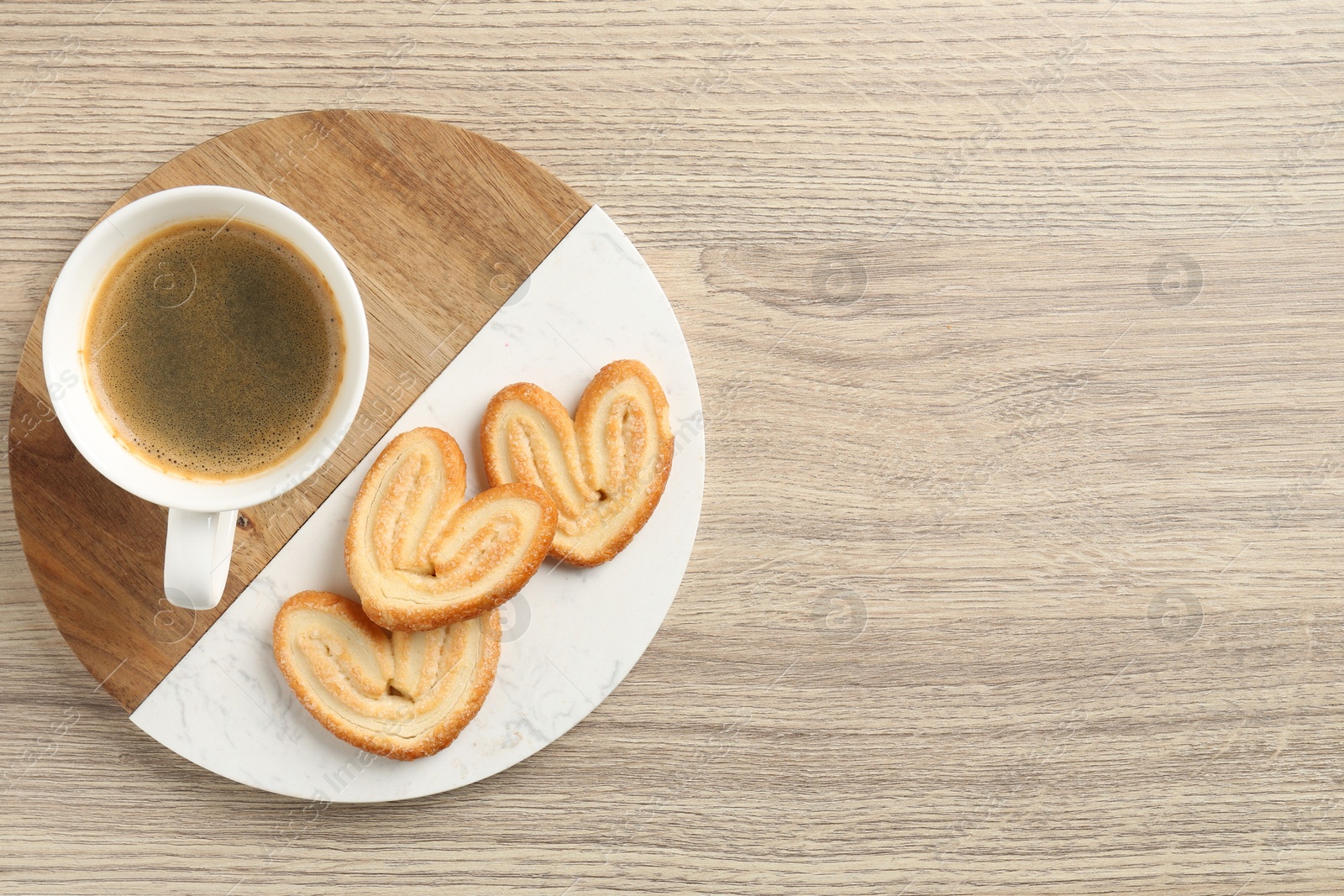 Photo of Delicious palmier cookies with coffee on wooden table, top view