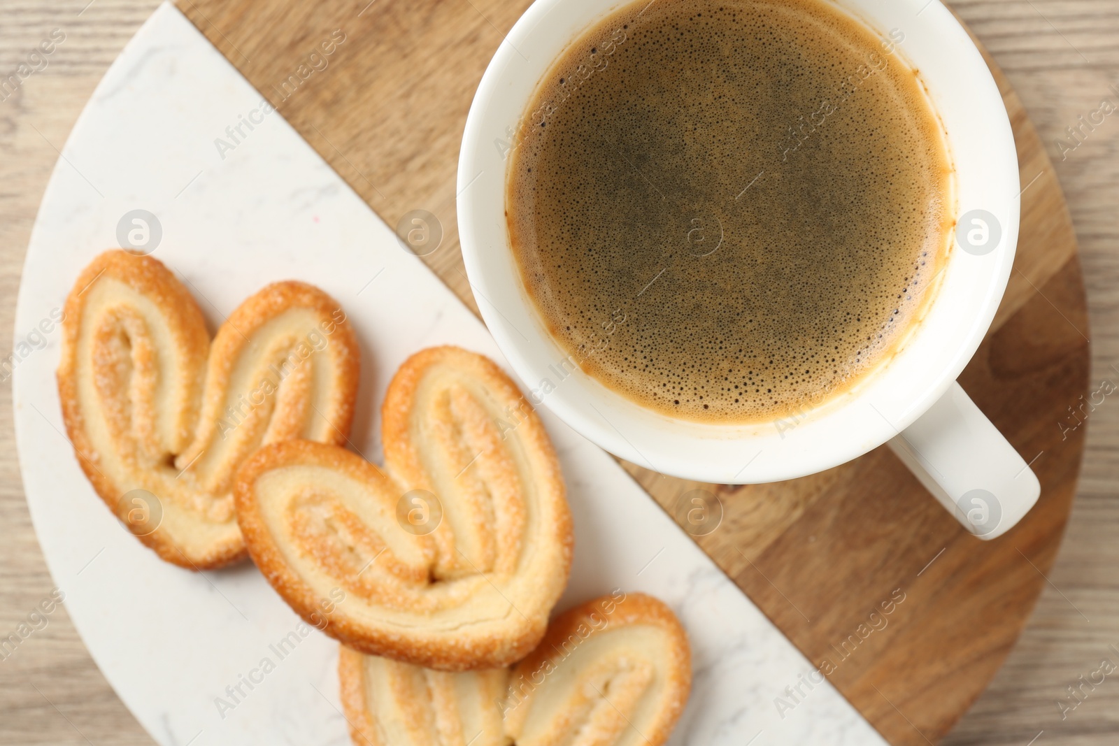 Photo of Delicious palmier cookies with coffee on wooden table, top view