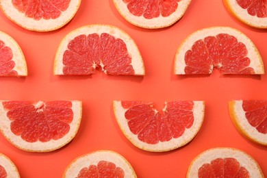 Photo of Slices of grapefruit in coral color background, flat lay