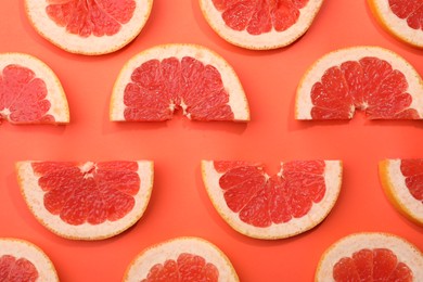 Photo of Slices of grapefruit in coral color background, flat lay