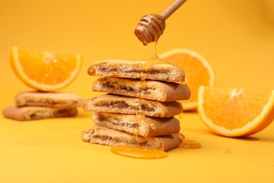 Photo of Pouring honey onto cookies on orange background, closeup