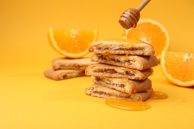 Pouring honey onto cookies on orange background, closeup. Space for text