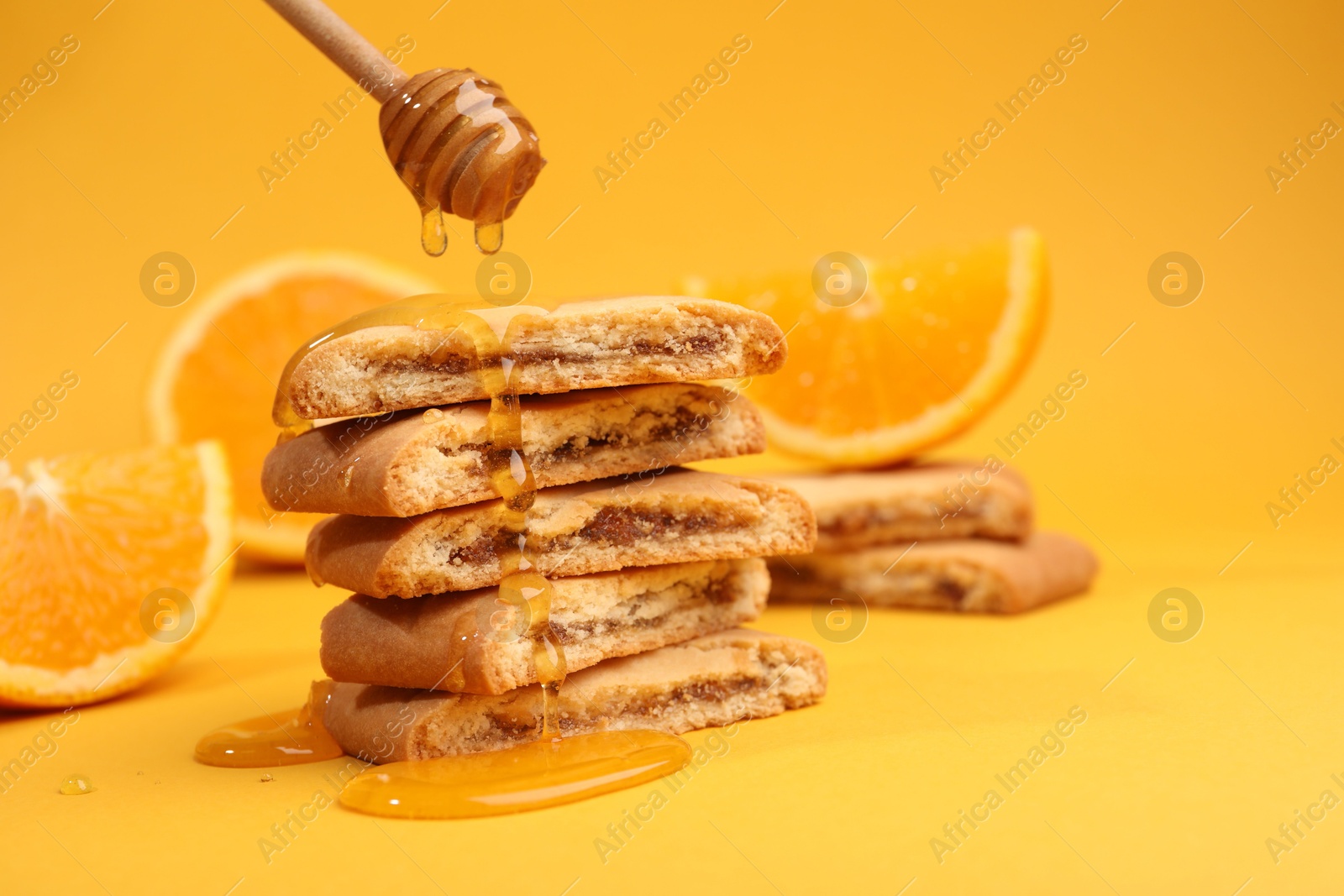 Photo of Pouring honey onto cookies on orange background, closeup. Space for text