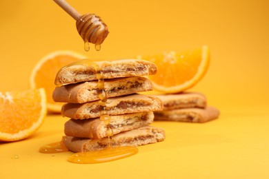 Photo of Pouring honey onto cookies on orange background, closeup. Space for text