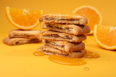 Tasty cookies with honey on orange background, closeup