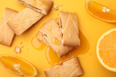 Photo of Tasty cookies with honey and orange slices on golden background, flat lay