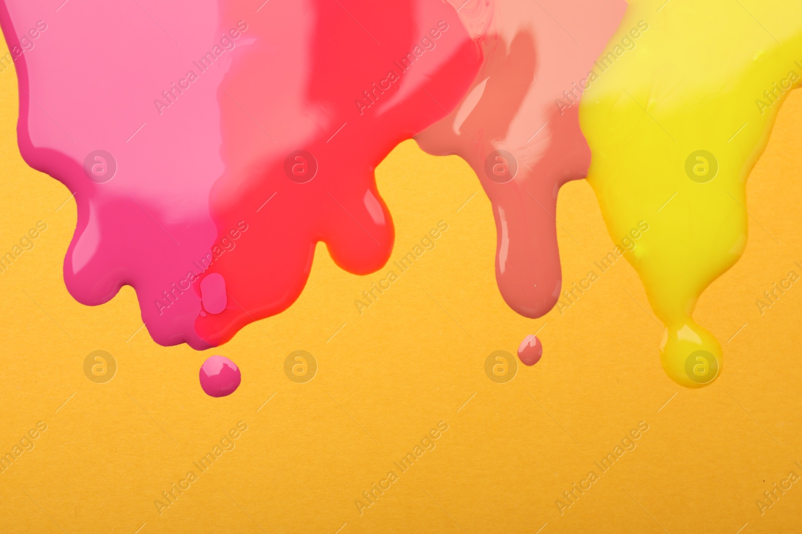 Photo of Different color nail polish flows on orange background