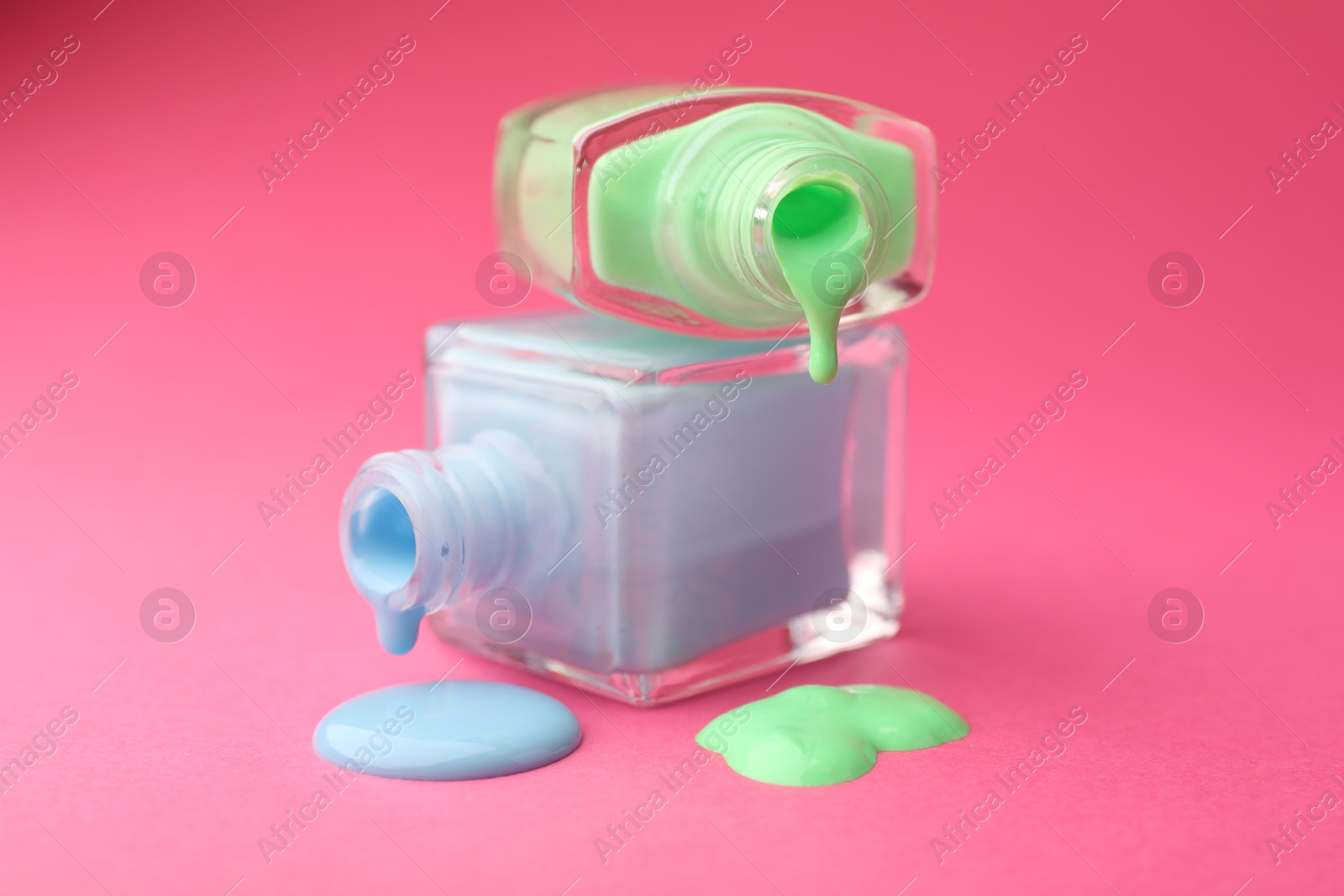 Photo of Bottles of nail polish on hot pink background