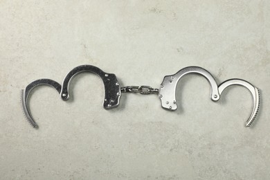 Photo of Classic chain handcuffs on grey table, top view