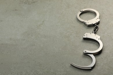 Photo of Classic chain handcuffs on grey table, space for text