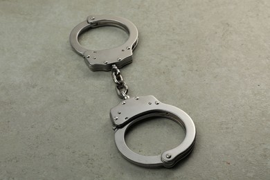 Photo of Classic chain handcuffs on grey table, closeup