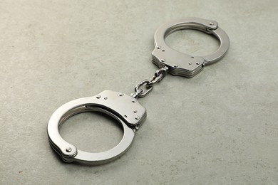 Photo of Classic chain handcuffs on grey table, closeup